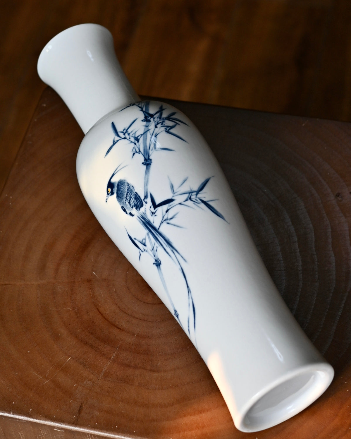Close-up detail of hand-painted long-tailed bird perched on bamboo branch
