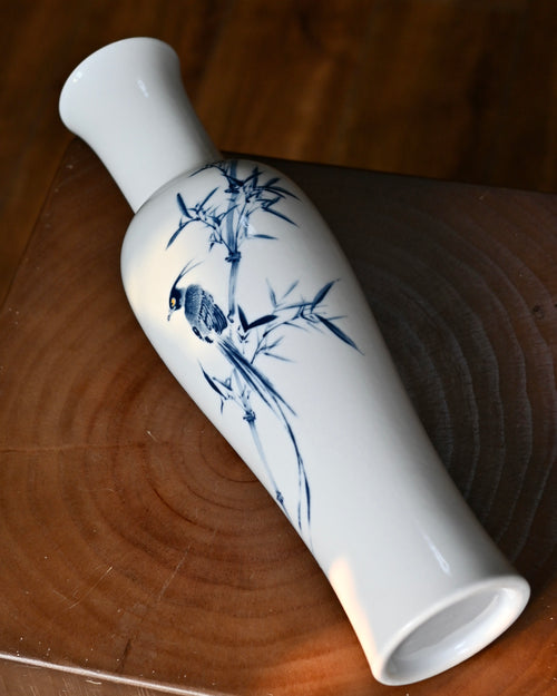 Close-up detail of hand-painted long-tailed bird perched on bamboo branch
